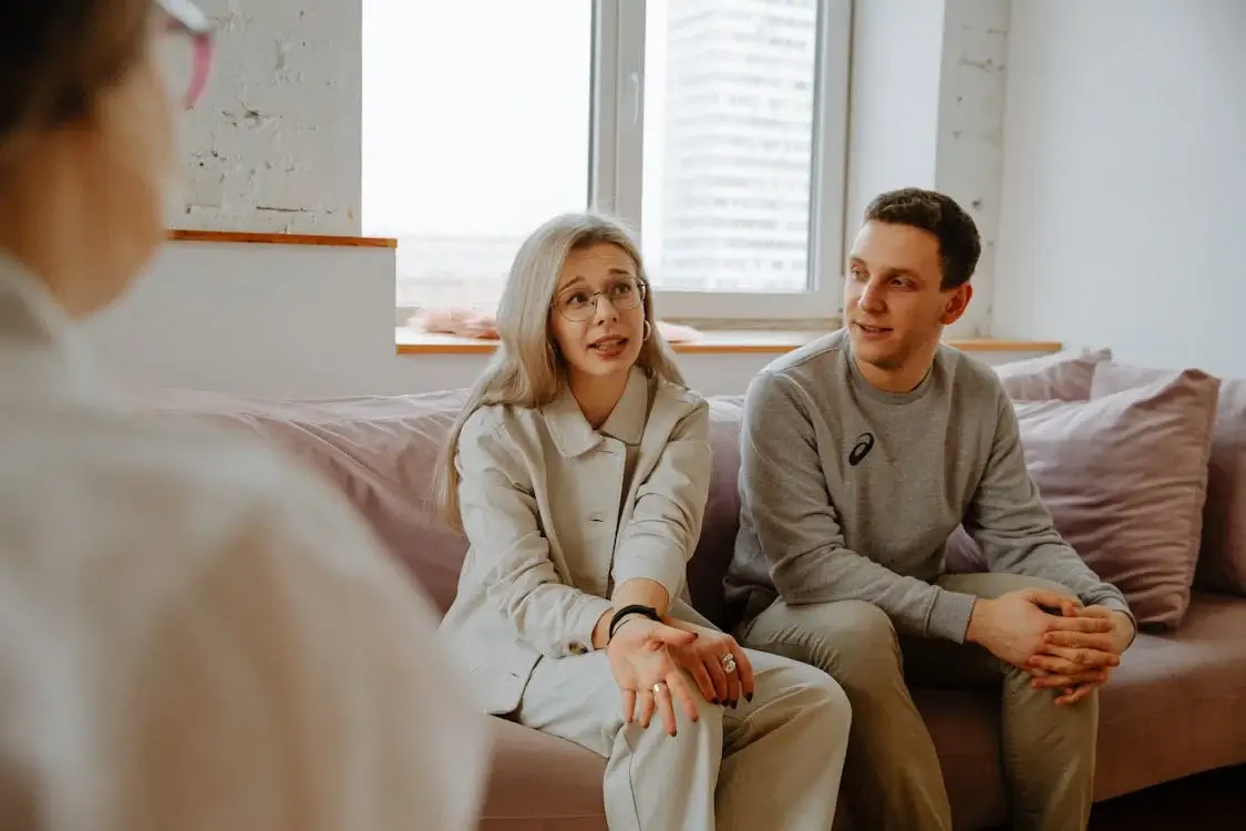 married couple on couch in conversation with therapist married couple on couch in conversation with therapist