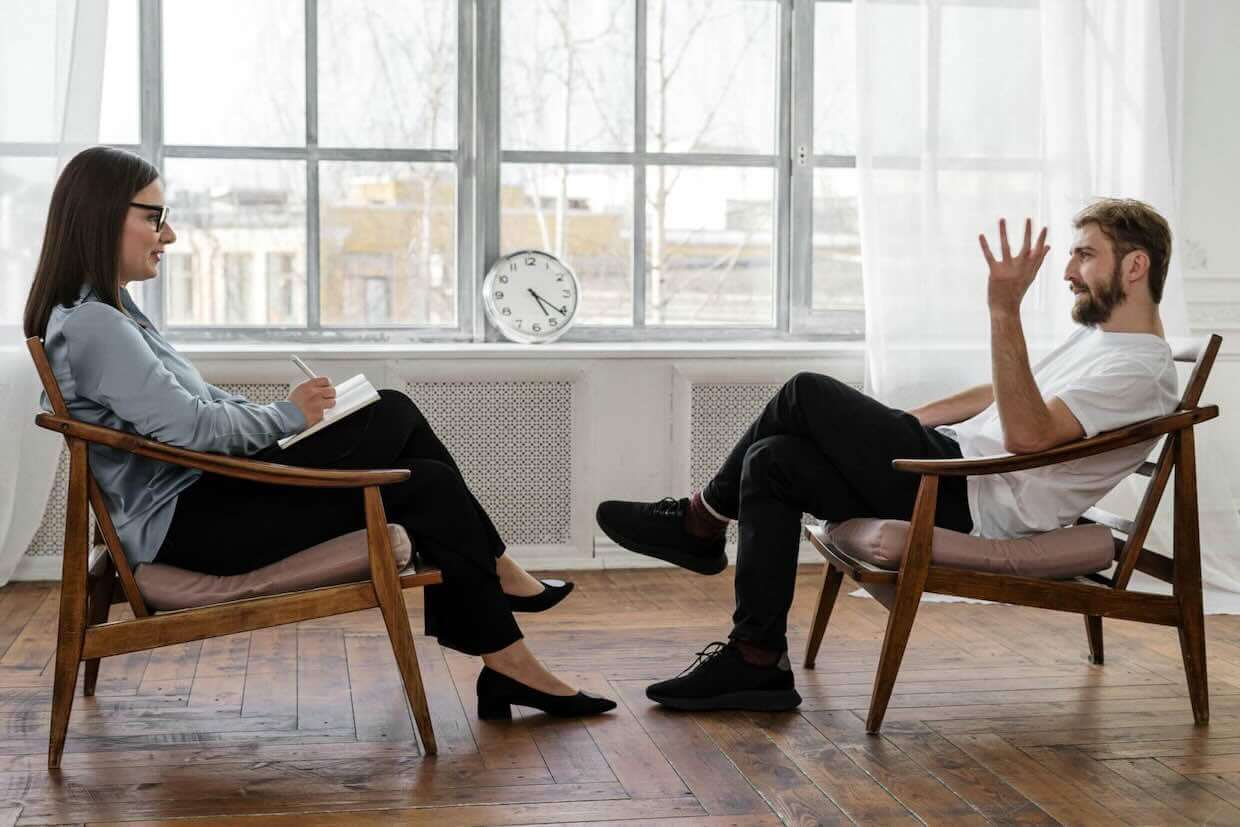 A man sitting across from a woman holding a notepad