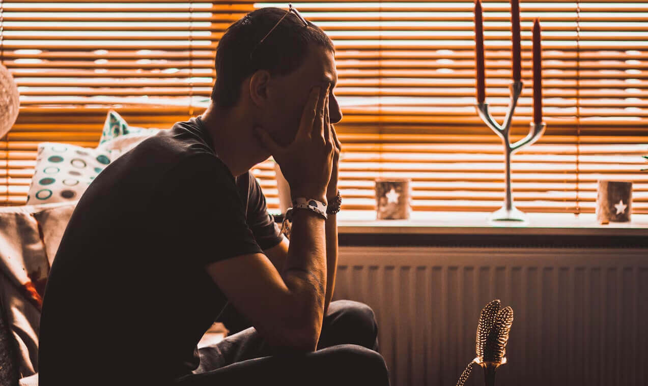seated person rubbing eyes, feeling stressed
